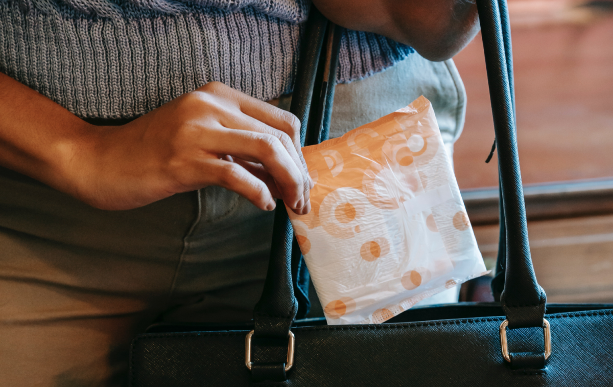 Una mujer guarda una compresa en su bolso / PEXELS