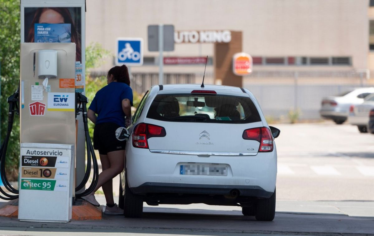 Una chica llena el depósito de gasolina de su coche / EP