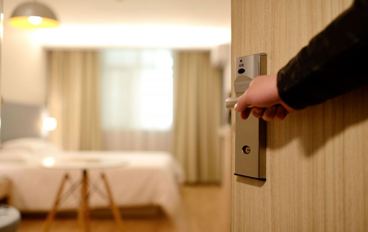 Una persona abre la puerta de su habitación de hotel / PEXELS