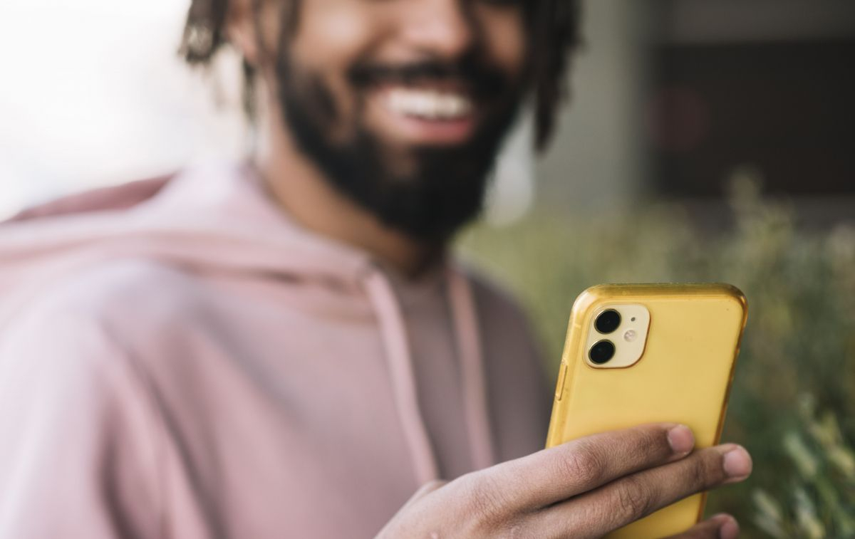 Un chico mira su iPhone de segunda mano de color amarillo / FREEPIK