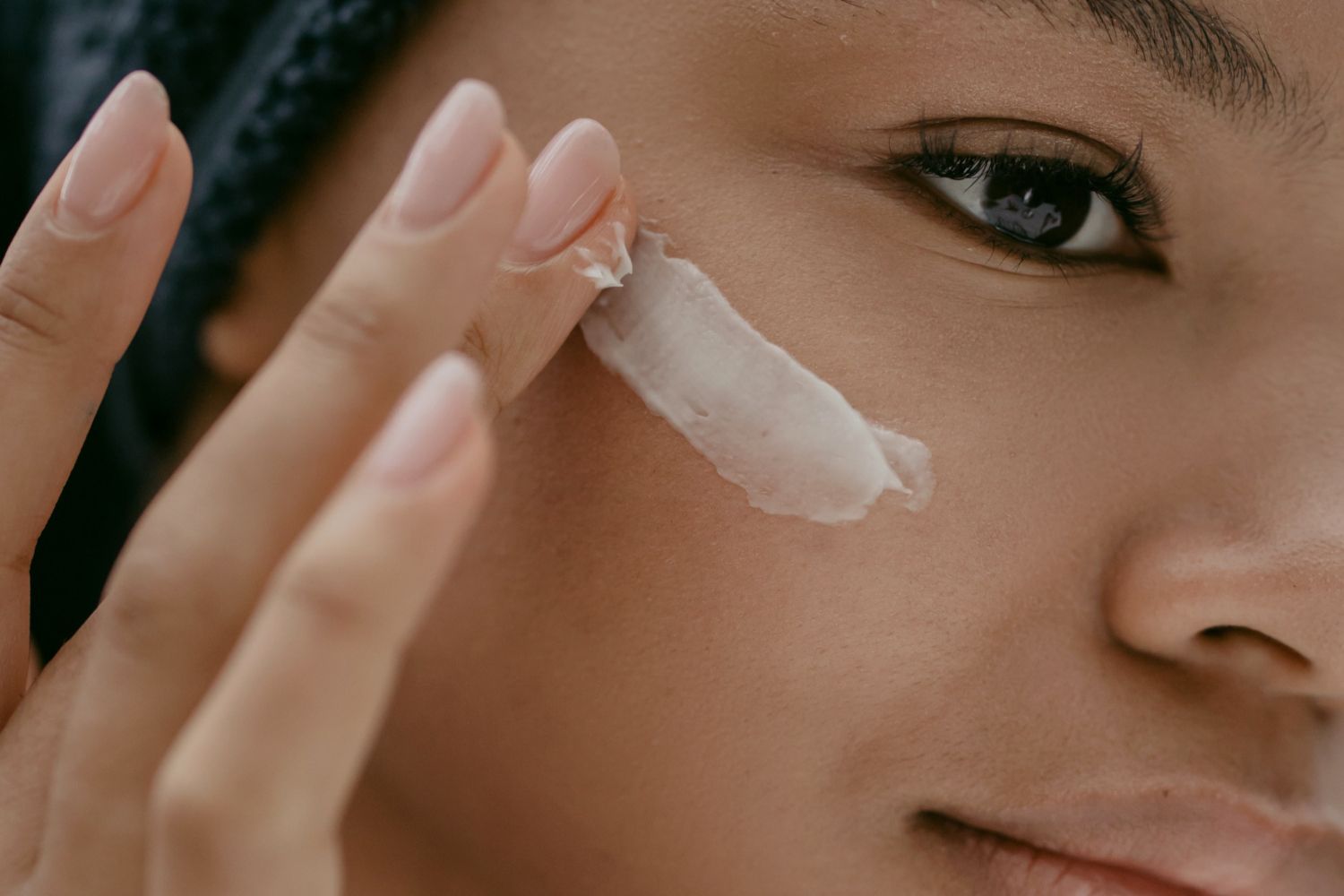 Una chica se aplica crema con un alto factor de protección / PEXELS