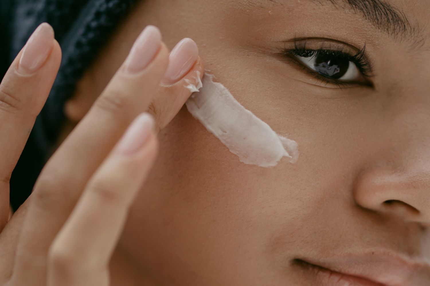 Una chica se aplica crema en la cara siguiendo ejercicios de yoga facial / PEXELS