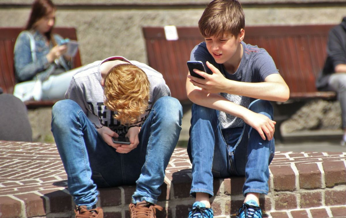 Dos jóvenes con sus teléfonos / PEXELS
