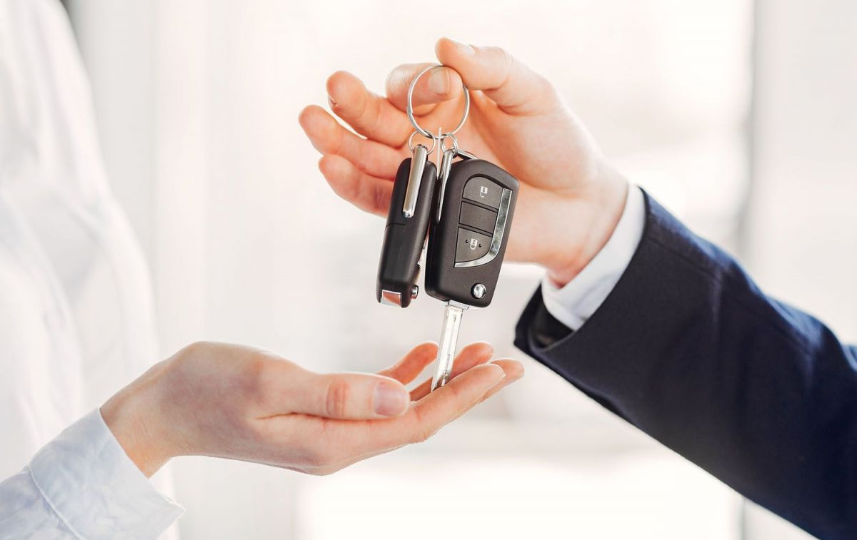 Un hombre entrega las llaves de un coche de alquiler a una persona con reserva / FREEPIK