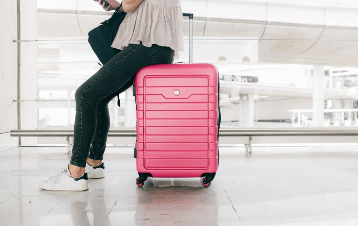 Una mujer se apoya sobre una maleta en un aeropuerto / PEXELS