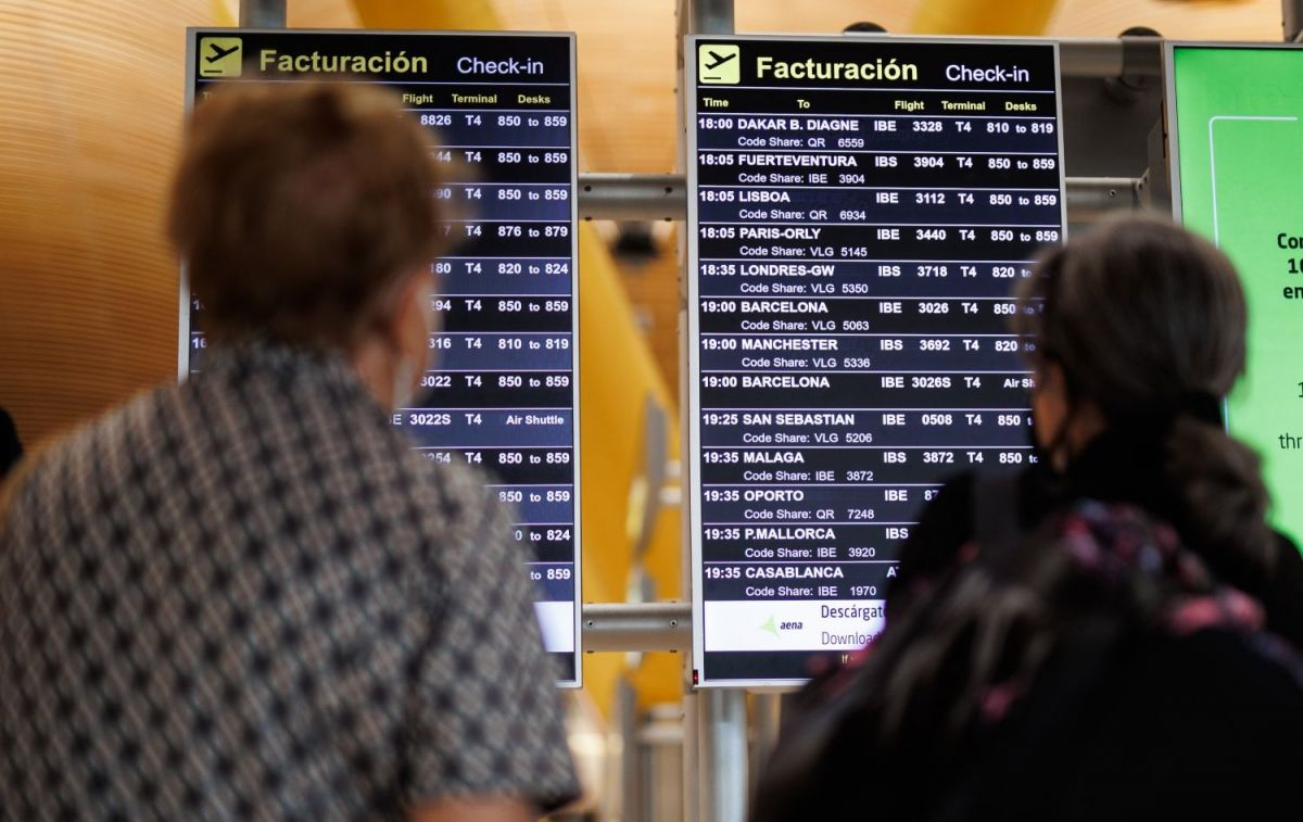 Dos personas miran el panel de facturación del aeropuerto Adolfo Suárez Madrid-Barajas / EP