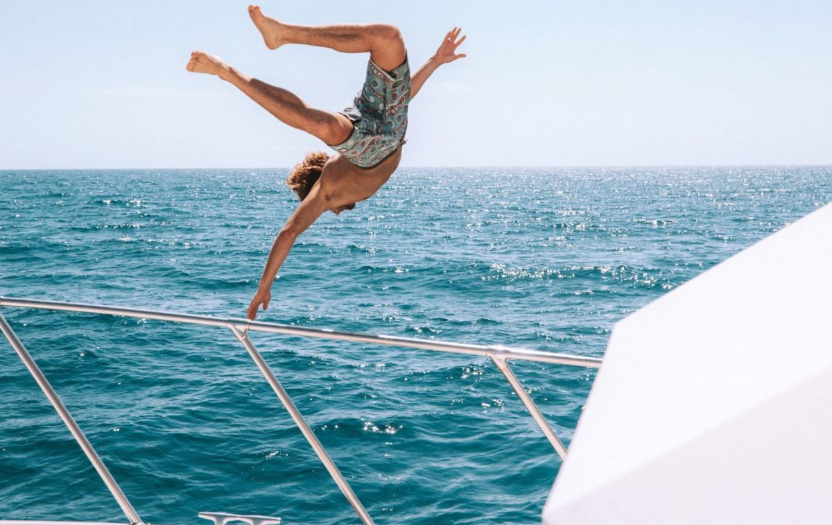 Un joven salta desde un barco / UNSPLASH