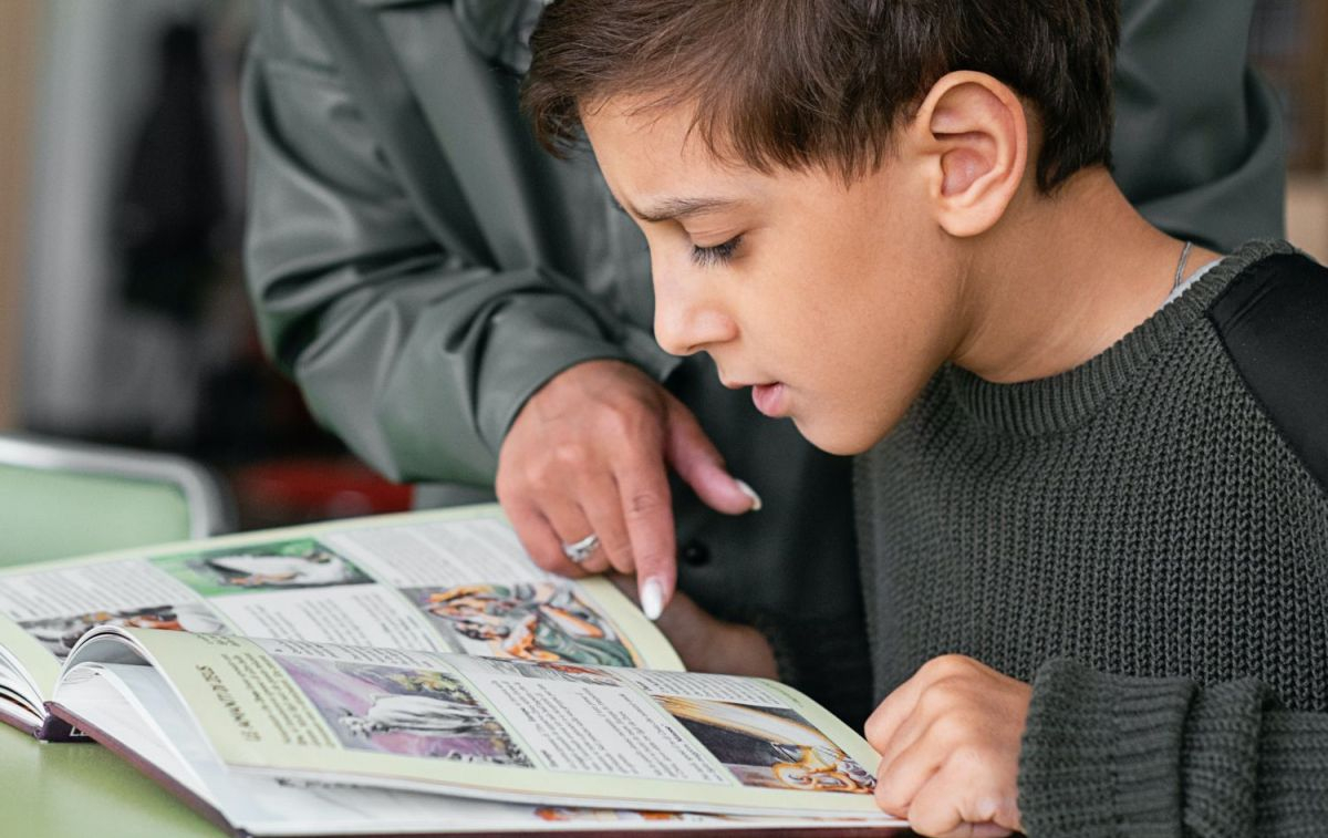 Un niño observa las páginas de un manual / PEXELS