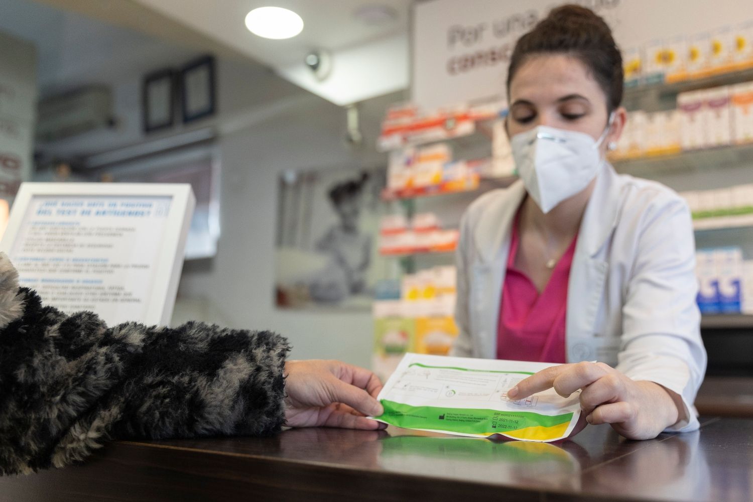 Una farmacéutica vende un test de antígenos a una clienta / EP