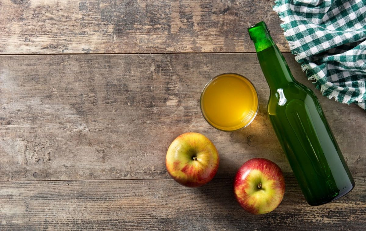 Una botella y un vaso de sidra junto a dos manzanas / FREEPIK