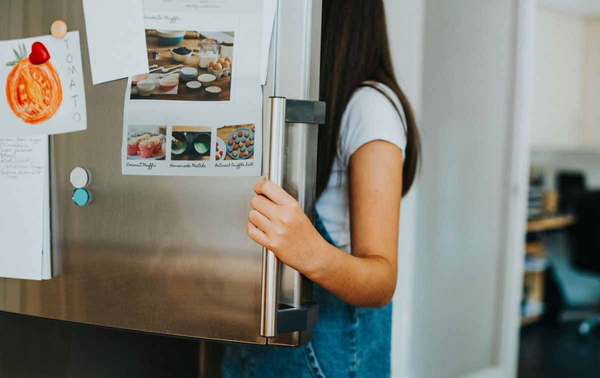 Una niña abriendo la puerta del frigorífico con congelador / FREEPICK