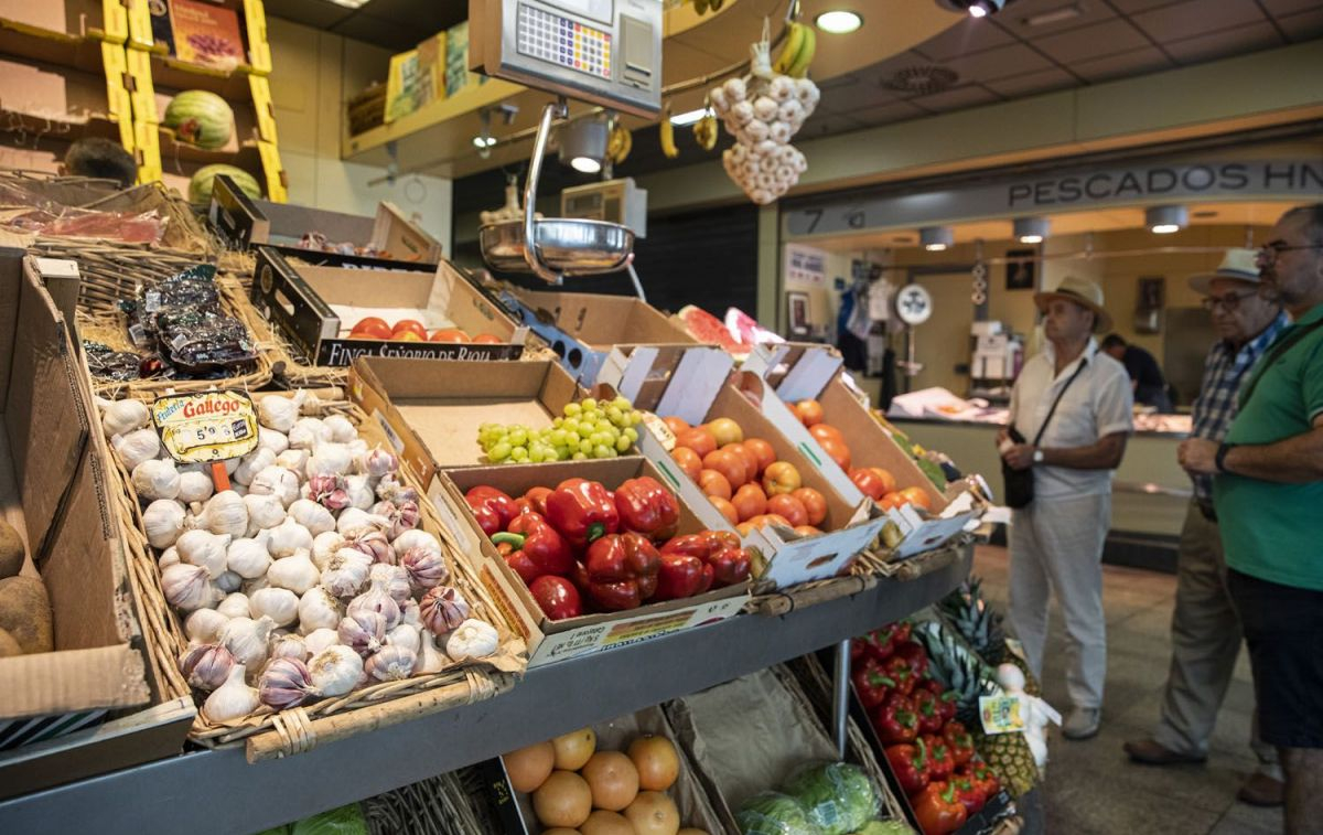 Varios consumidores esperan su turno en un comercio y miran los precios de los alimentos / EP