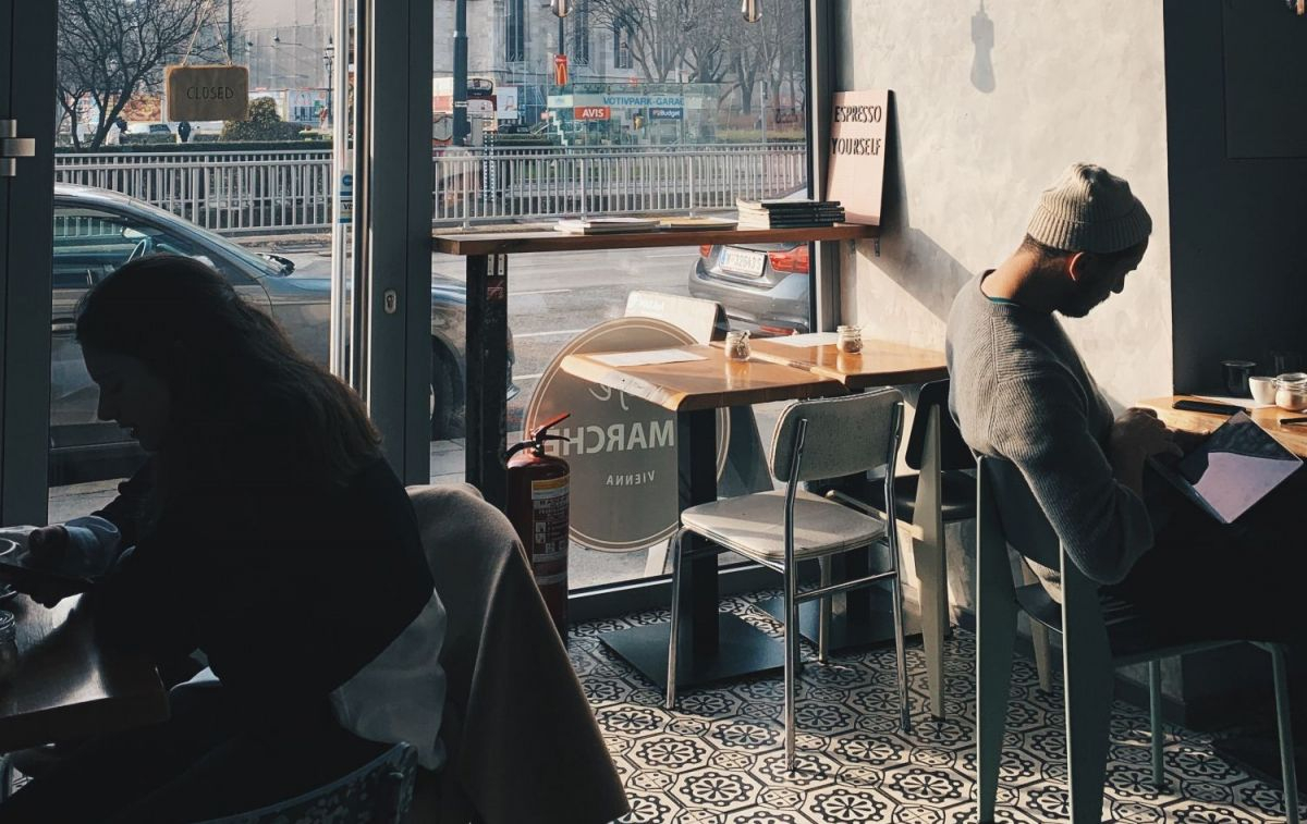Un hombre lee en una cafetería mientras cae la tarde / UNSPLASH