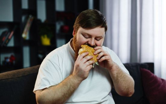 Un hombre con sobrepeso devora una hamburguesa / FREEPIK Un hombre con sobrepeso devora una hamburguesa / FREEPIK