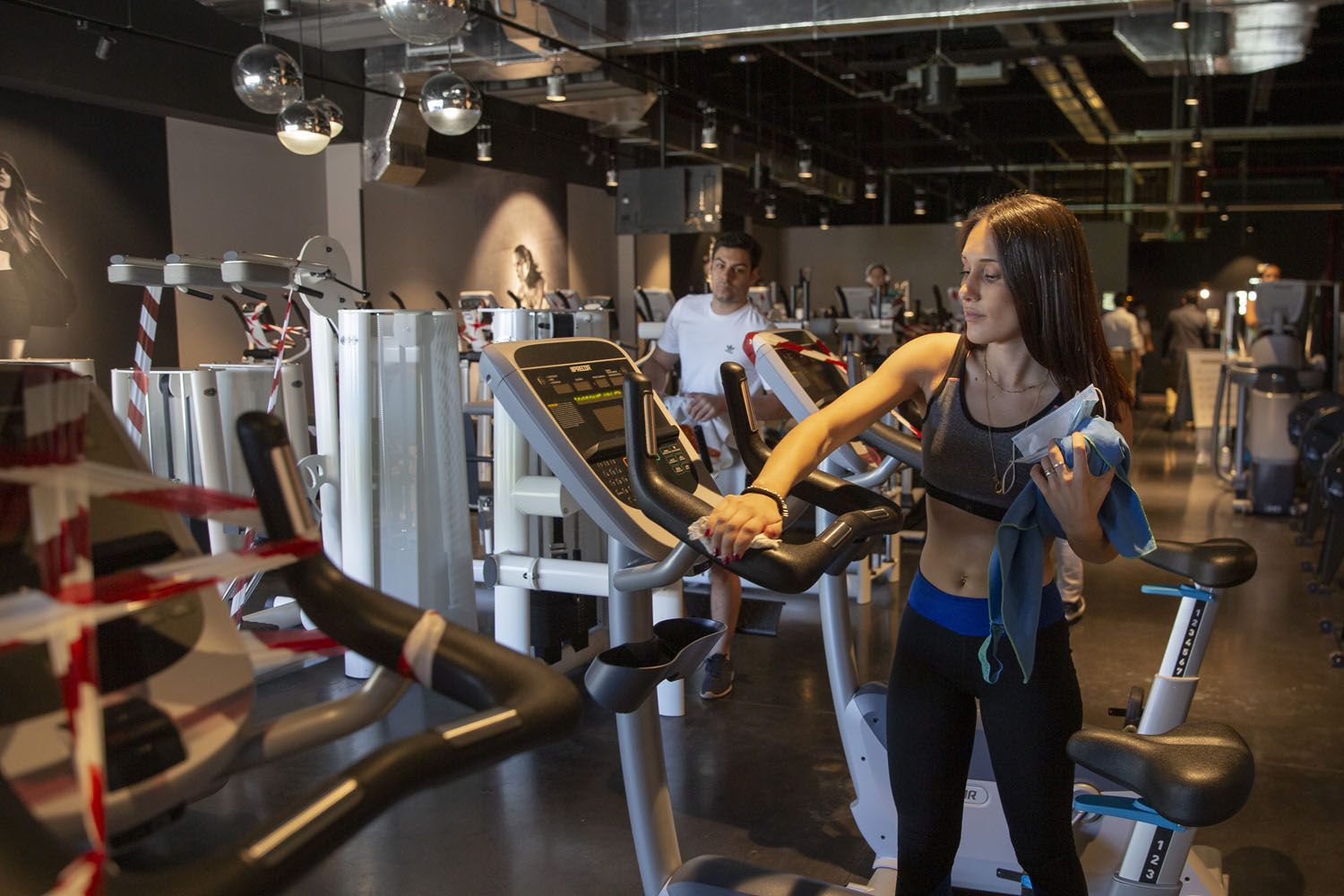 Una usuaria limpia una máquina tras hacer ejercicio en un gimnasio McFit / EP Una usuaria limpia una máquina tras hacer ejercicio en un gimnasio McFit / EP