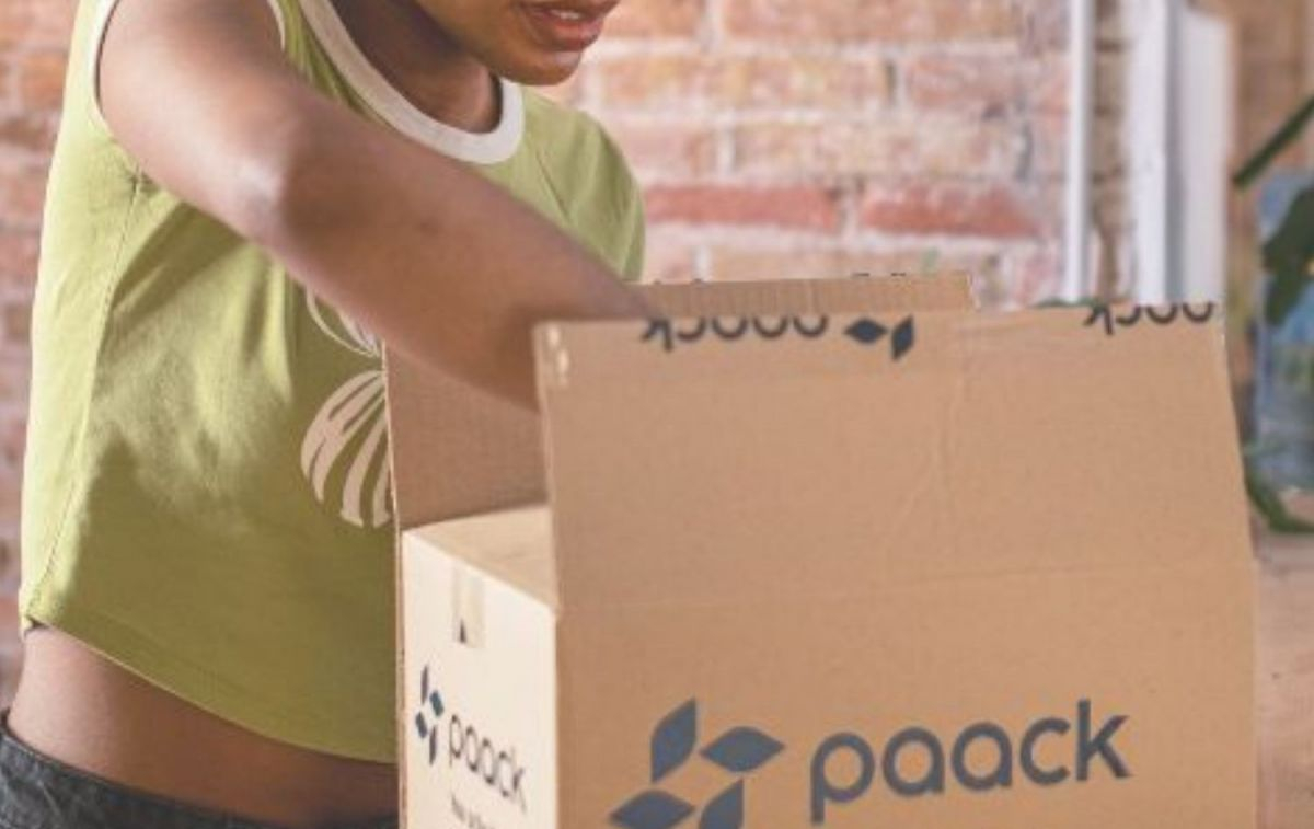Una mujer abre un paquete con el logo de Paack / PAACK