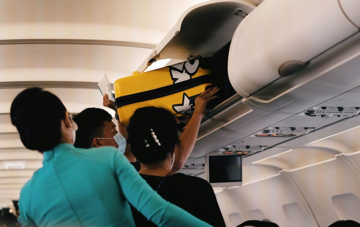 Un pasajero coloca su maleta de cabina y su equipaje de mano en un avión / PEXELS