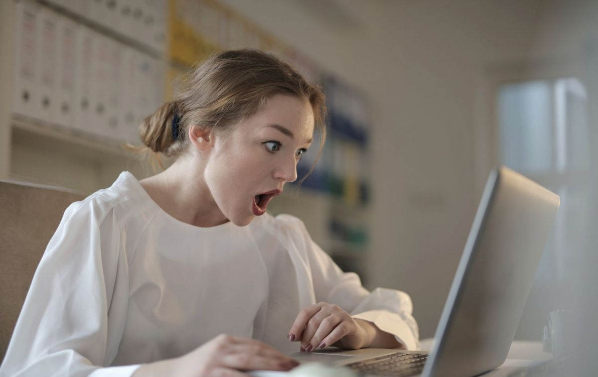 Una mujer sorprendida frente a su ordenador / PEXELS