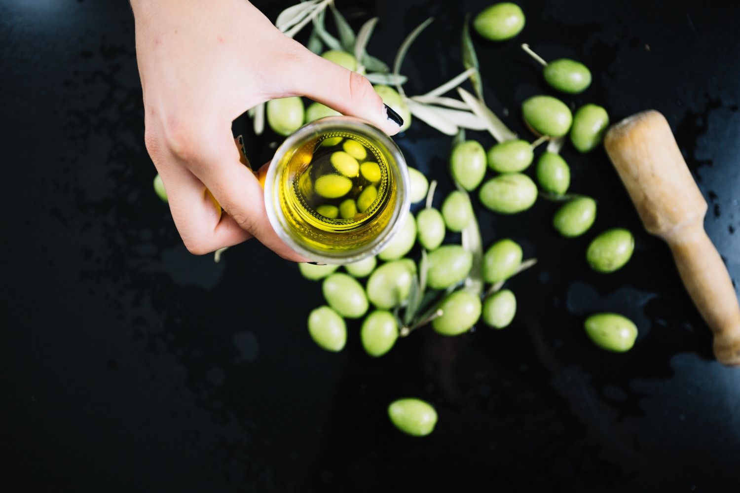 Un vaso de aceite de oliva virgen extra y unas aceitunas / FREEPIK