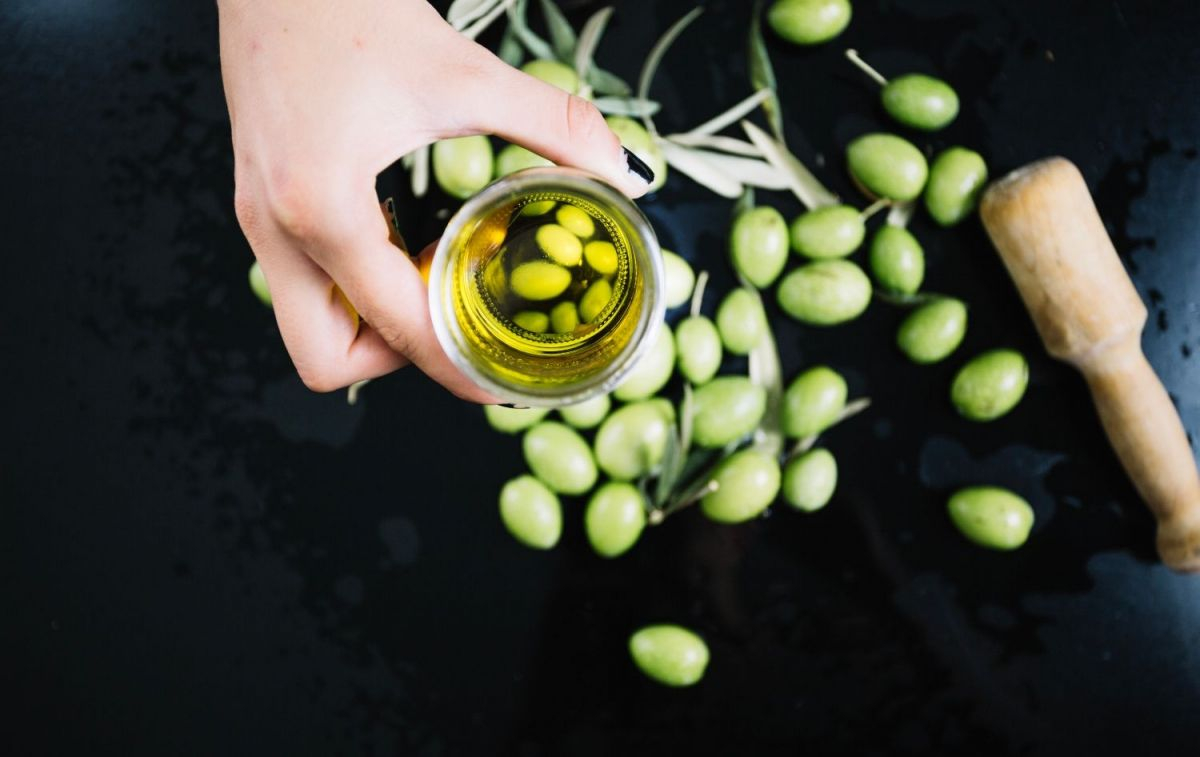 Un vaso de aceite de oliva virgen extra y unas aceitunas / FREEPIK