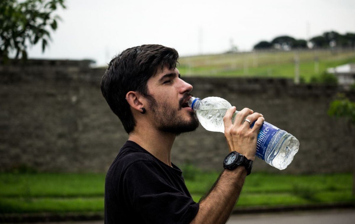 Una persona con una botella de agua embotellada / PEXELS