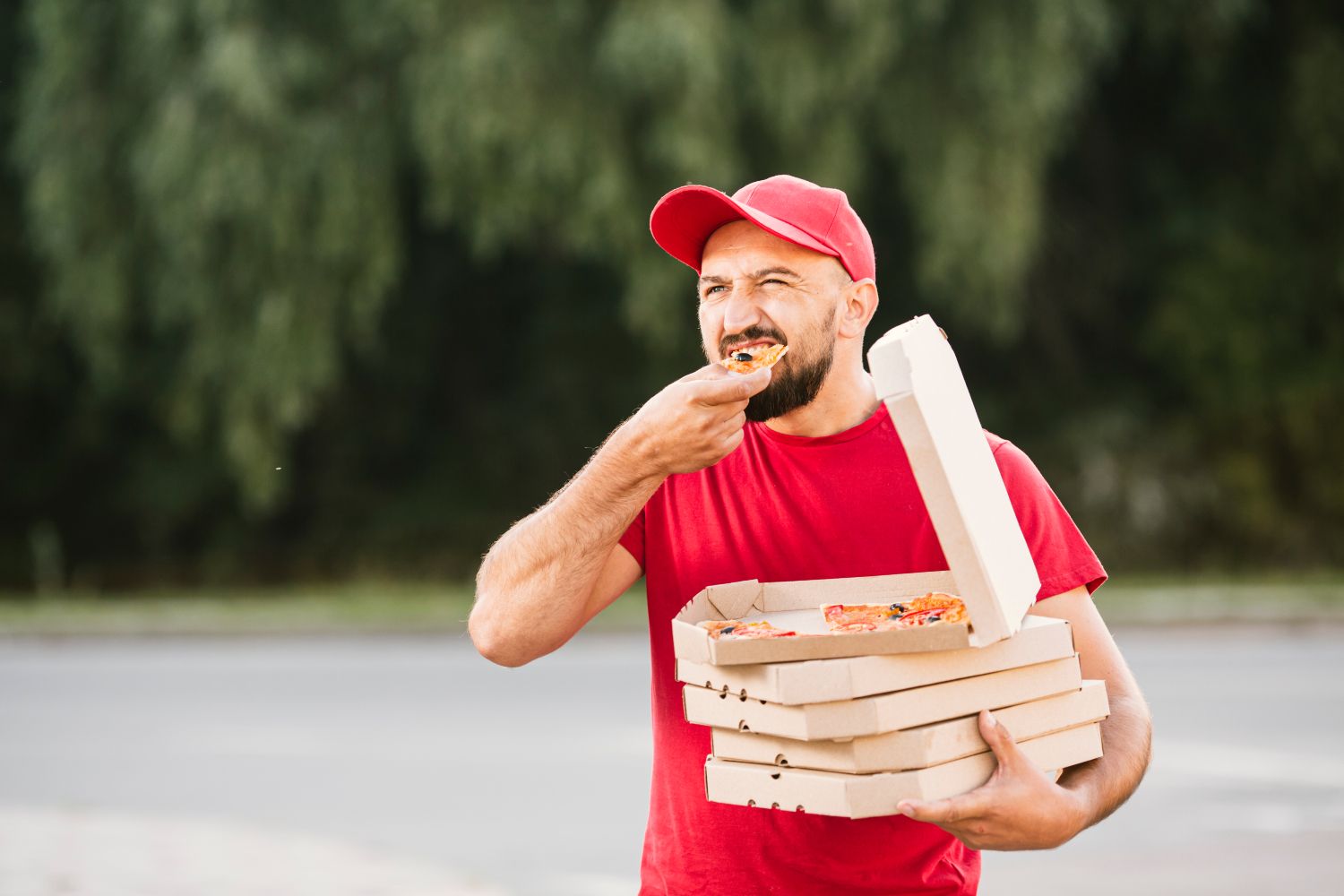 Un repartidor come un trozo de pizza rápido y de pie/ FREEPIK