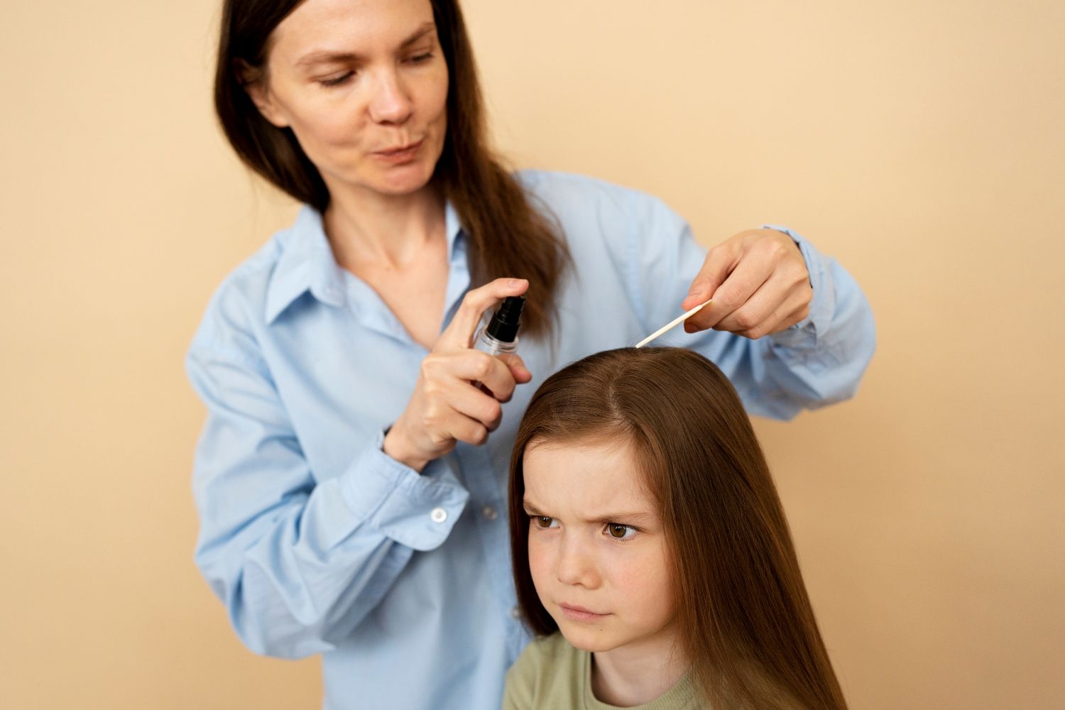 Una madre aplica una loción antipiojos a su hija / FREEPIK