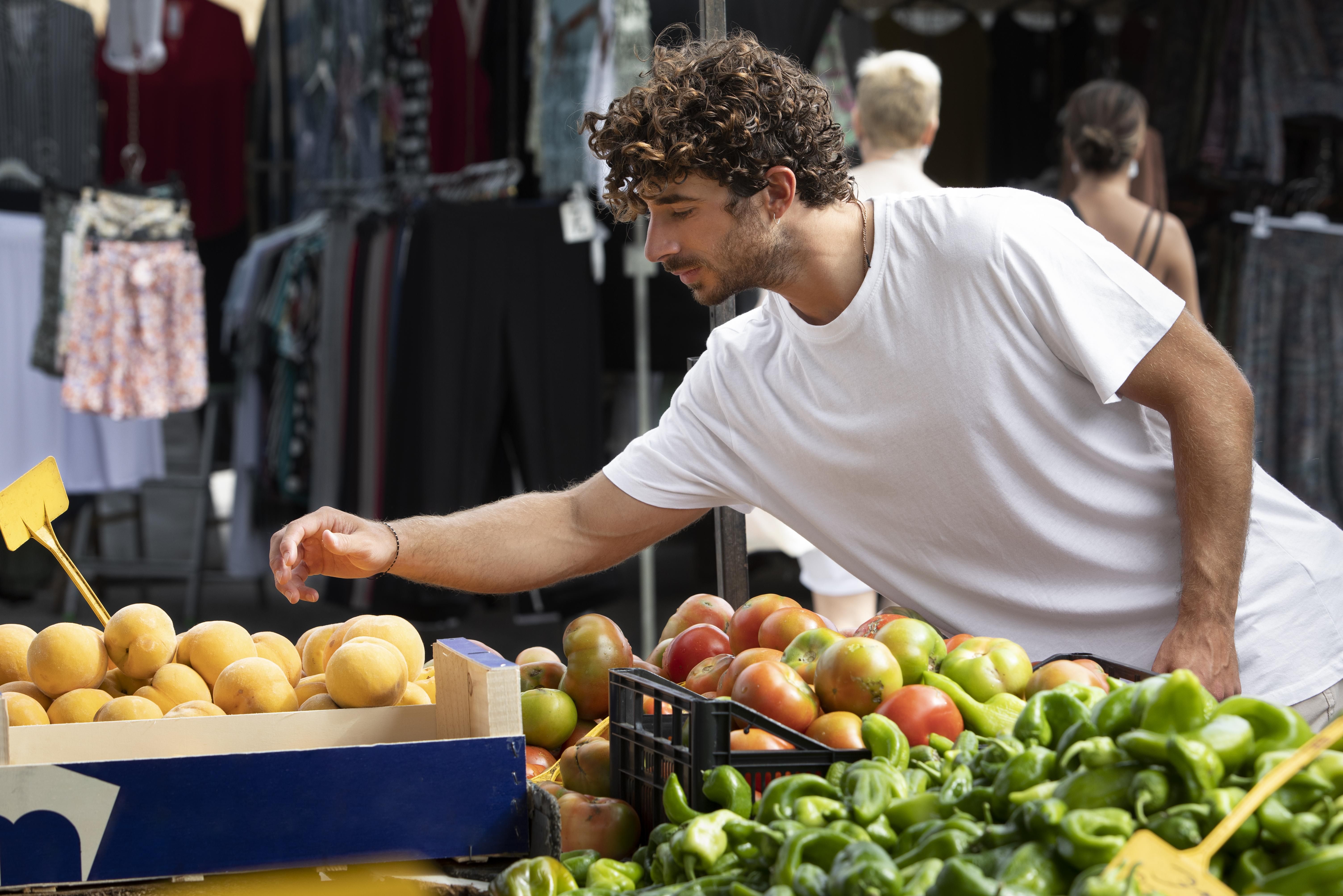 Un joven compra frutas y patatas, algunos de los alimentos que más se encarecen / FREEPIK