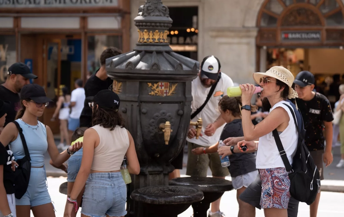 Varias personas se refrescan para evitar el calor en la fuente de Canaletas / David Zorrakino - EP