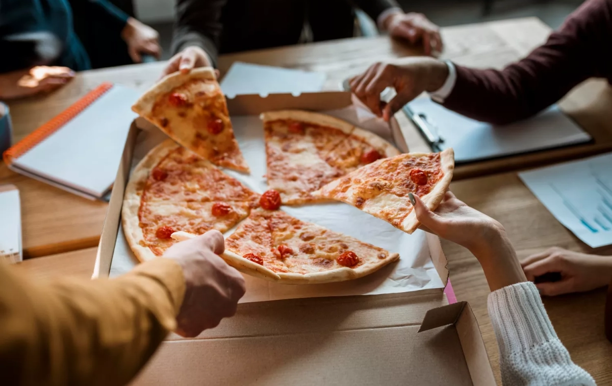 Varias personas comparten una pizza / FREEPIK