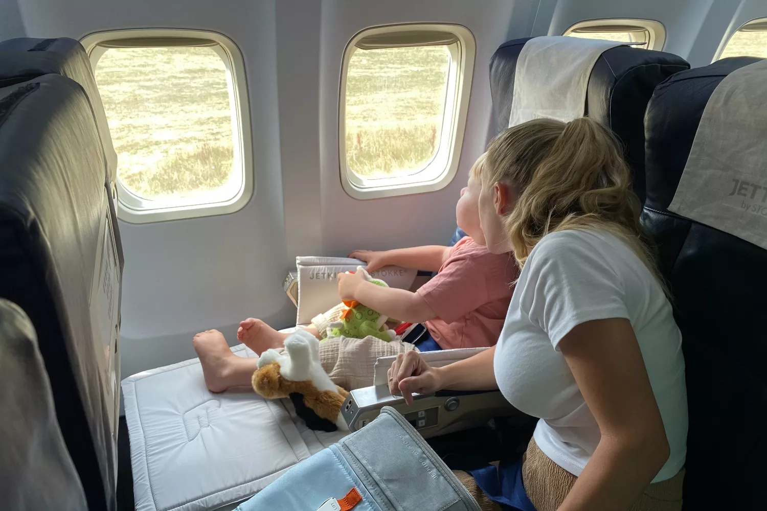 Un niño junto a su madre montando en una avión / PEXELS