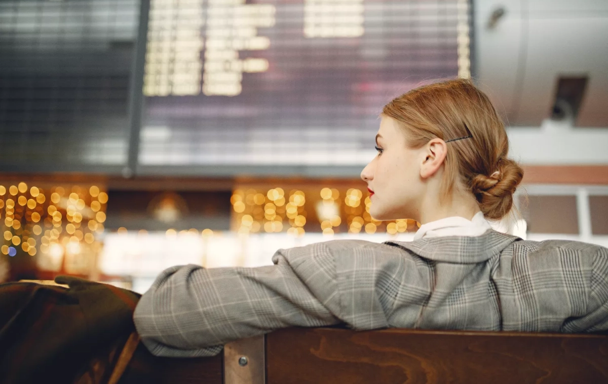 Una mujer espera a que salga el vuelo de una aerolínea / PEXELS
