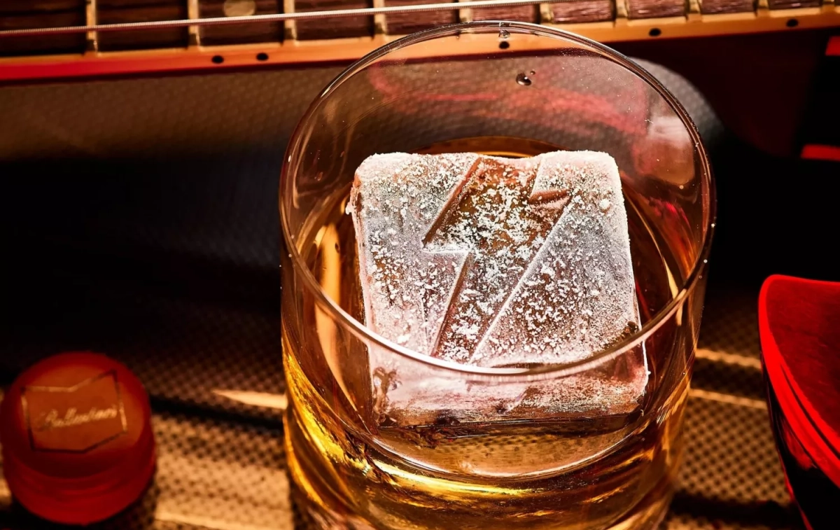Un vaso de whisky y un hielo con el icónico rayo de la banda AC/DC / BALLANTINE'S