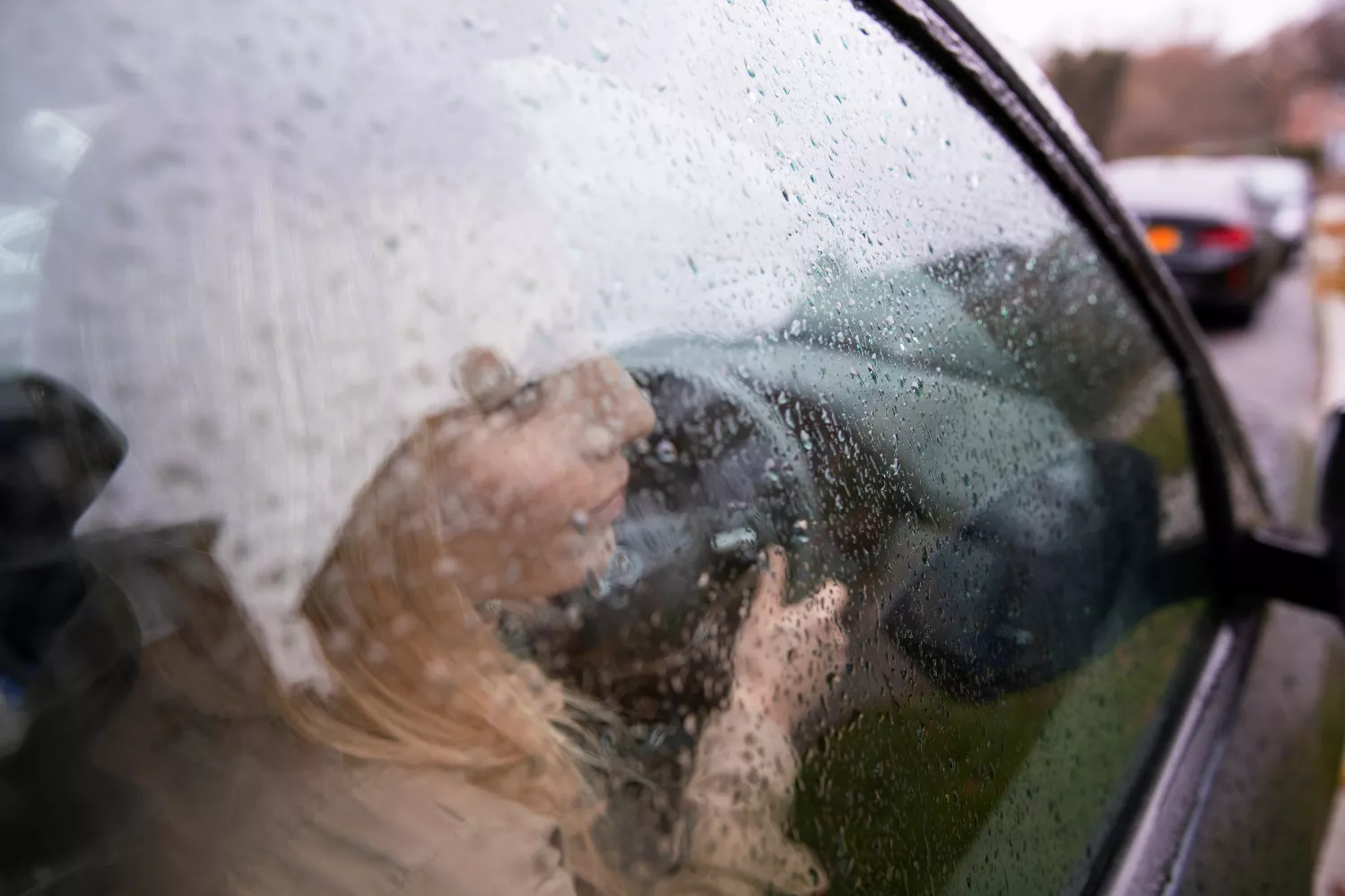 Una mujer dentro de un coche con los cristales empañados por la lluvia / FREEPIK