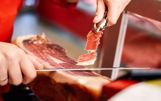 Un profesional corta un jamón serrano ibérico/ FREEPIK - @javi_indy