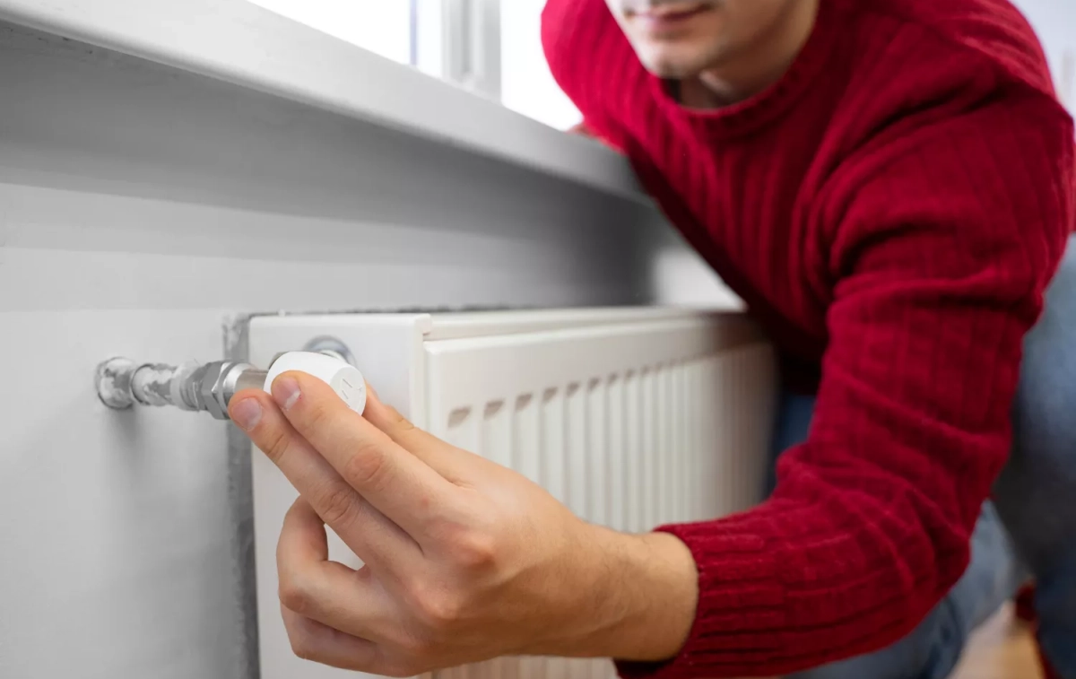 Una persona cierra un radiador para ahorrar en calefacción / FREEPIK