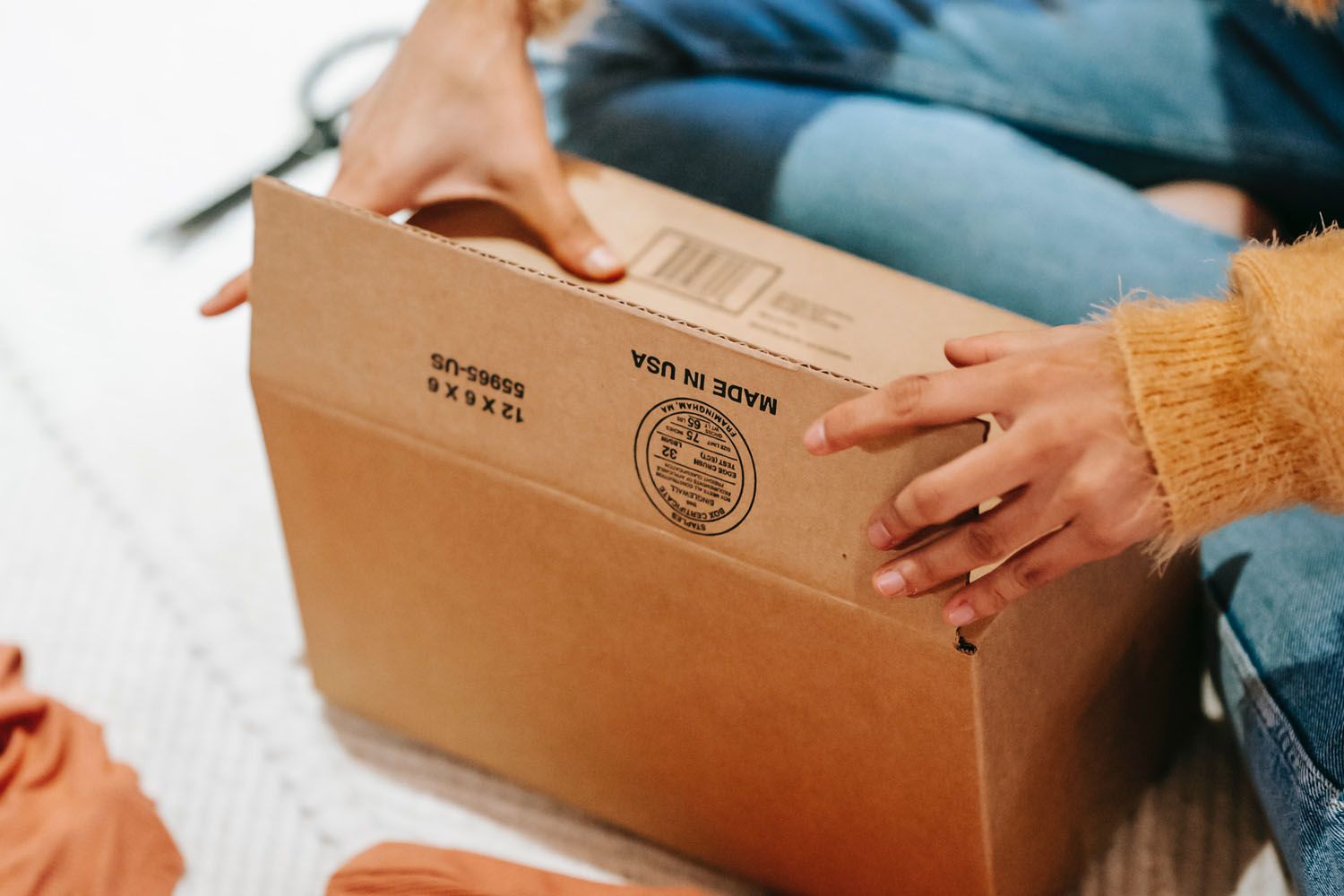 Una mujer abre un paquete enviado desde Estados Unidos / PEXELS