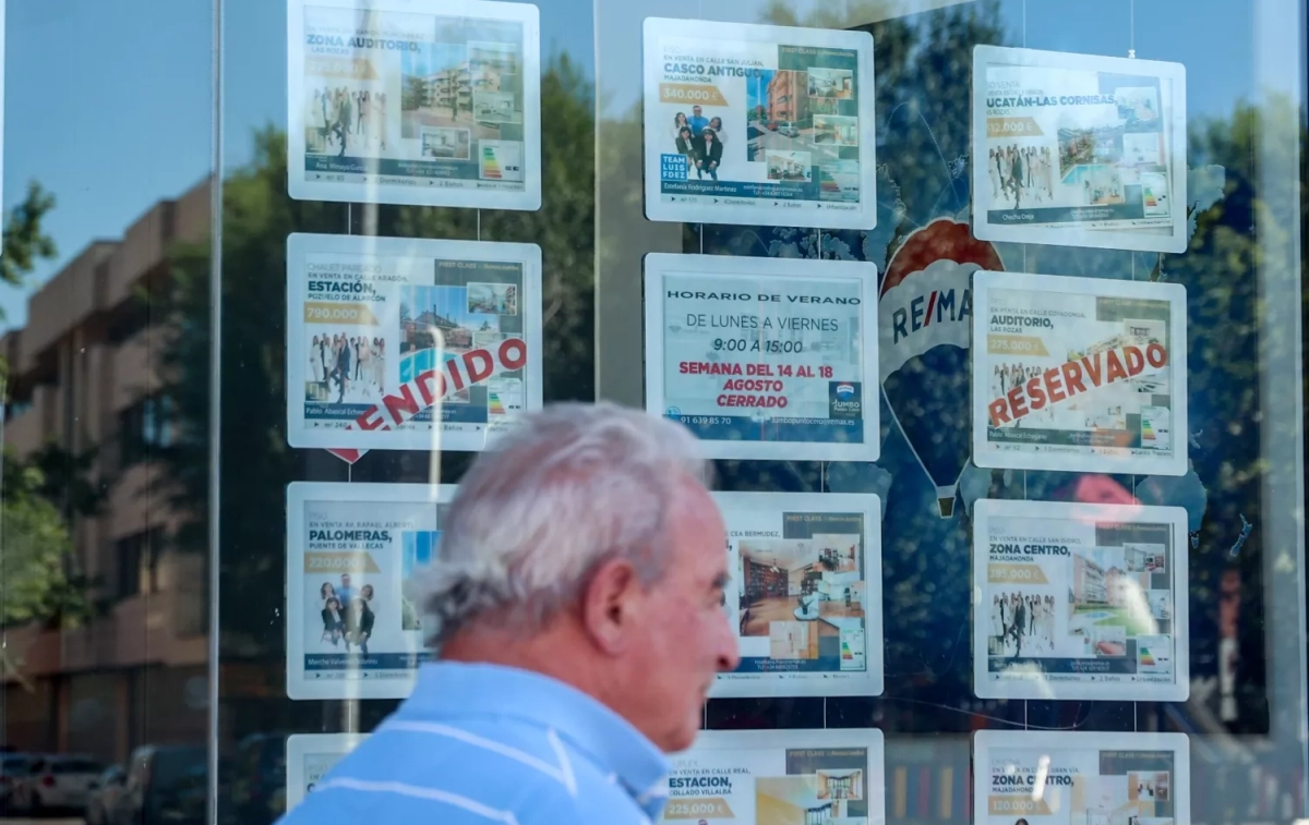 Un hombre camina frente a un escaparate de anuncios de vivienda / Ricardo Rubio - EP Un hombre camina frente a un escaparate de anuncios de vivienda / Ricardo Rubio - EP