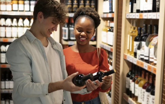 Dos personas miran vinos en una tienda / FREEPIK