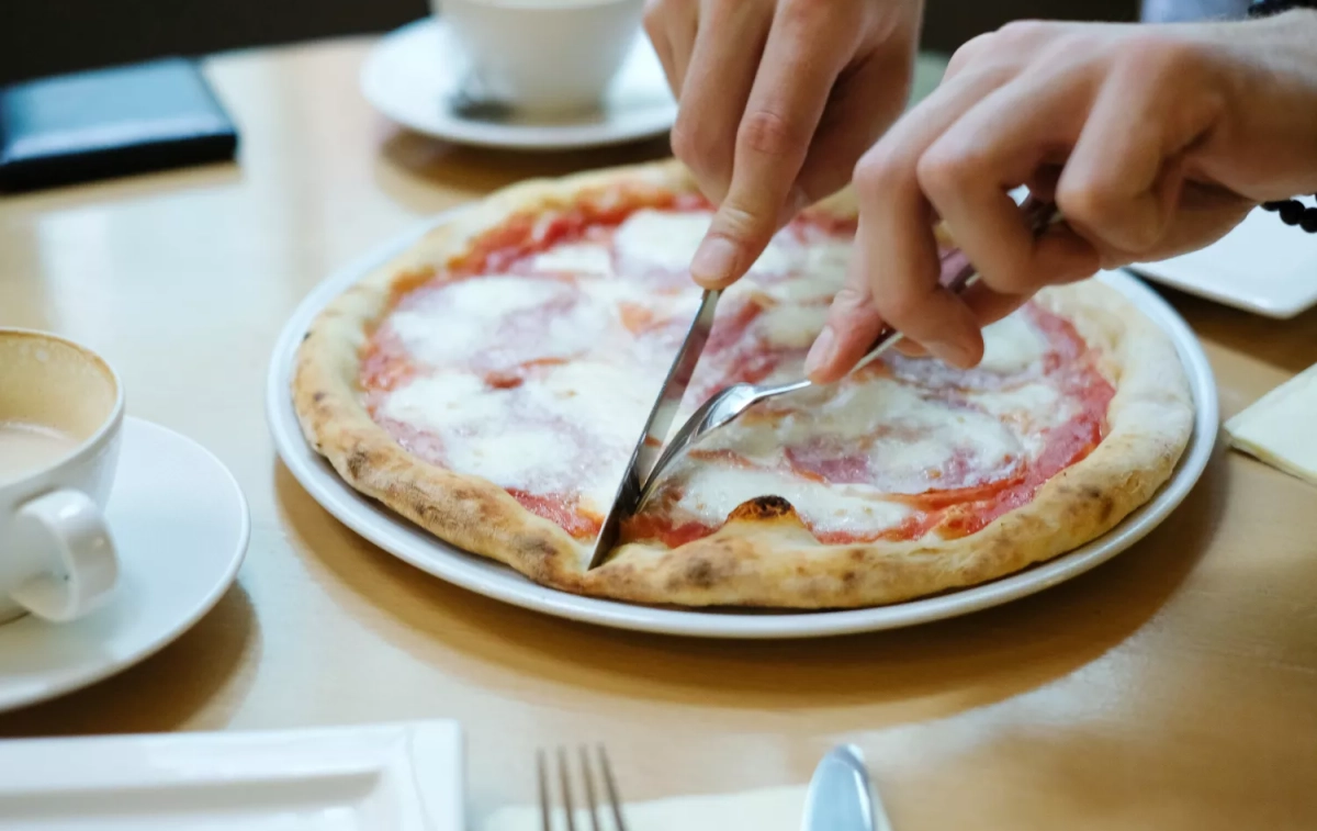 Una persona parte una pizza con cubiertos, algo que, desde ahora, se puede hacer en Telepizza / FREEPIK - @Racool_studio Una persona parte una pizza con cubiertos, algo que, desde ahora, se puede hacer en Telepizza / FREEPIK - @Racool_studio