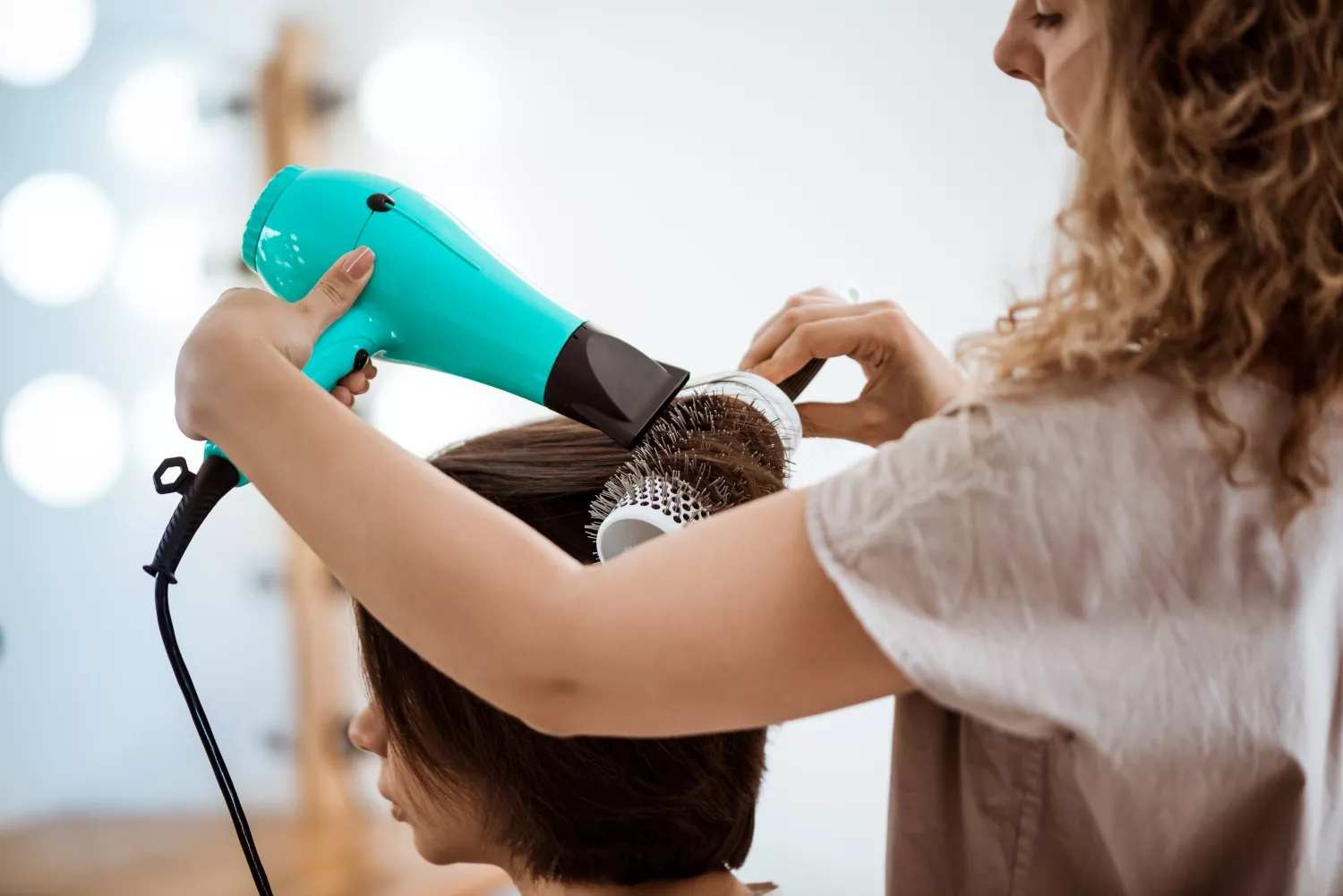 Una peluquera peina a una clienta / FREEPIK