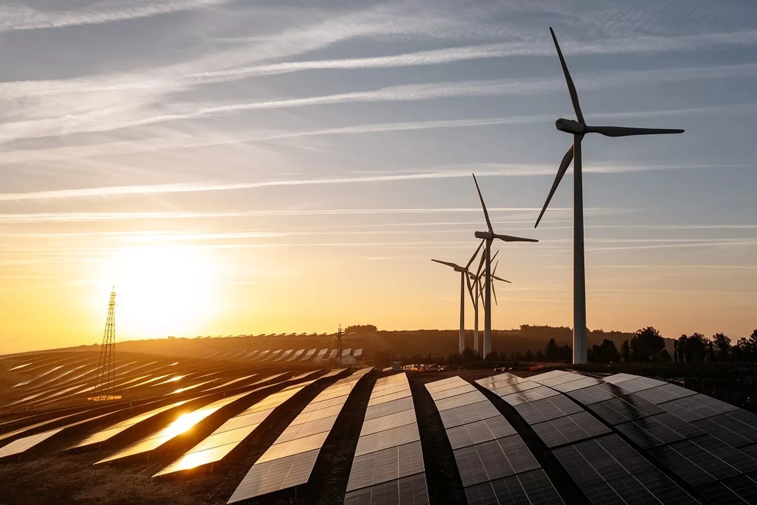 Unos molinos y la luz del sol reflejada en una instalación de placas solares / EDP RENEWABLES