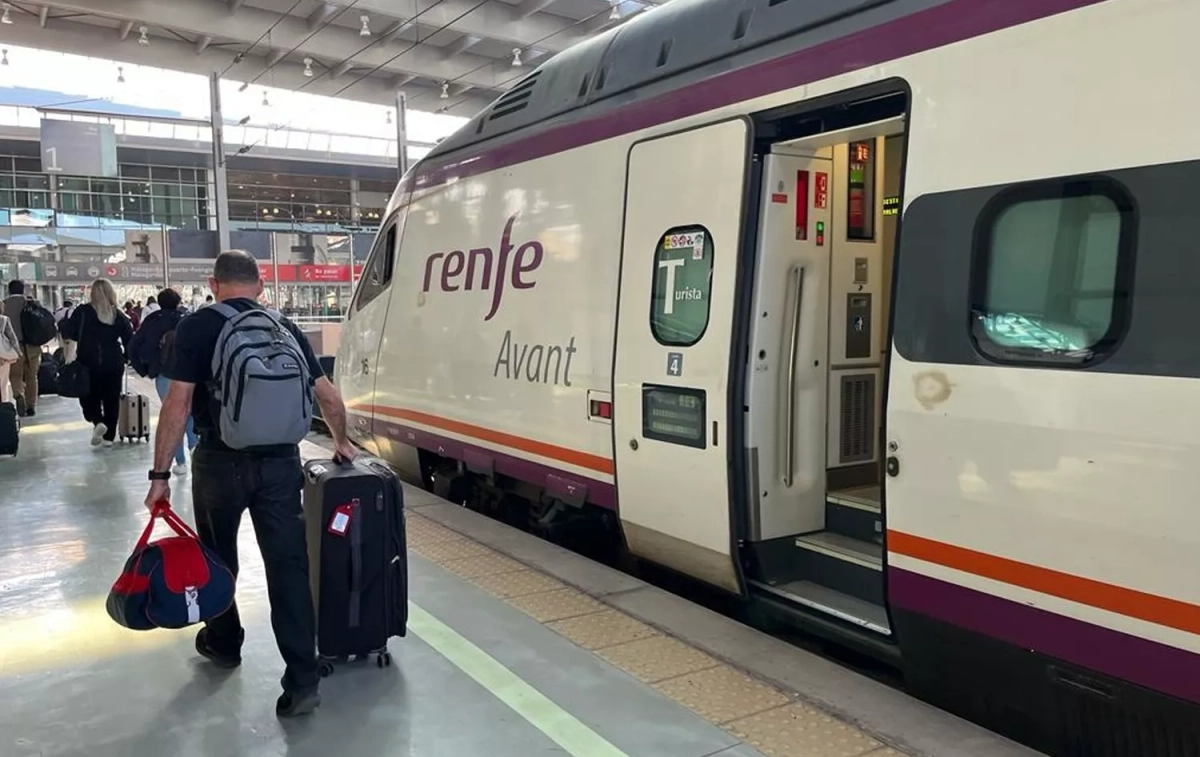 Pasajeros caminando por el andén frente a un tren Avant / RENFE