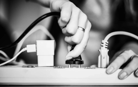 Una persona enchufa un cable más a su regleta / FREEPIK
