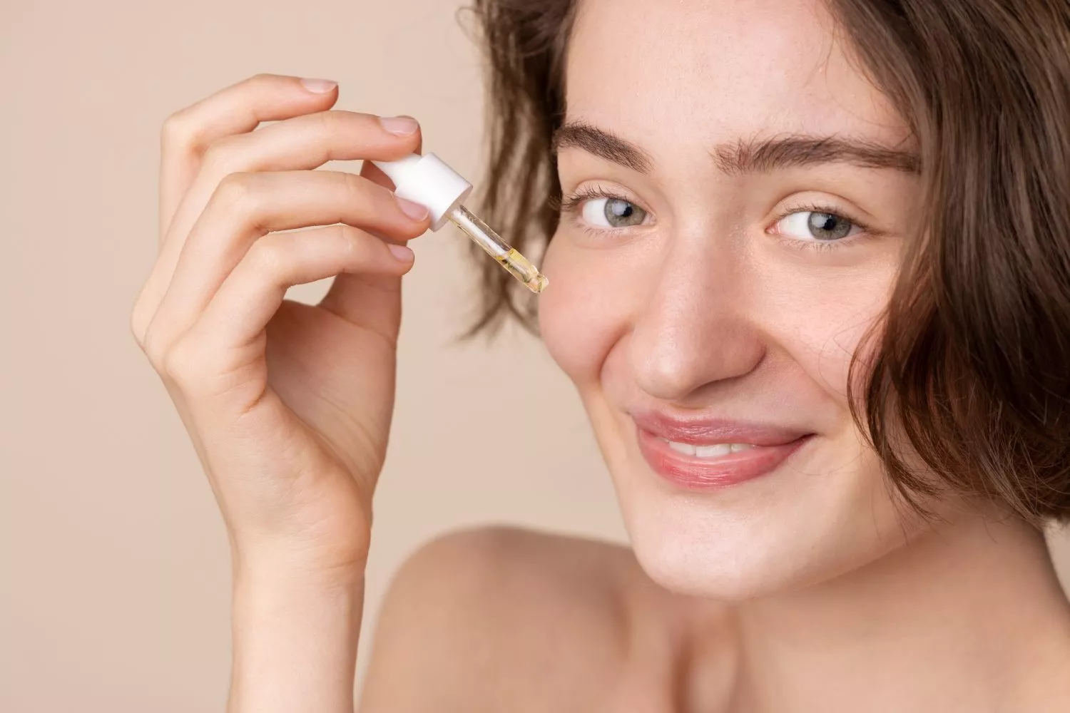Una chica con la piel grasa se aplica un sérum facial   FREEPIK
