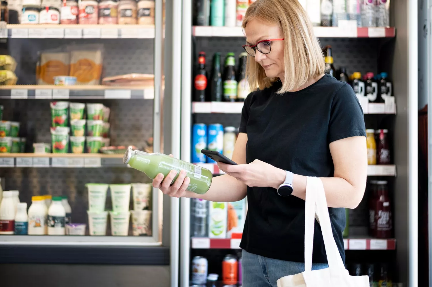 Uma mulher no supermercado compra uma bebida de marca própria / FREEPIK