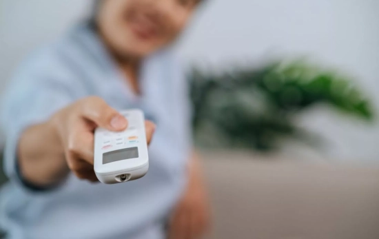 Una persona controla el aire acondicionado a la hora en que la luz es más económica / FREEPIK