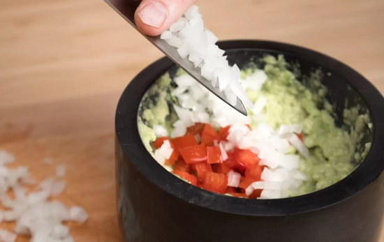 Una persona agrega cebolla a un plato con salmón y aguacate / FREEPIK Una persona agrega cebolla a un plato con salmón y aguacate / FREEPIK