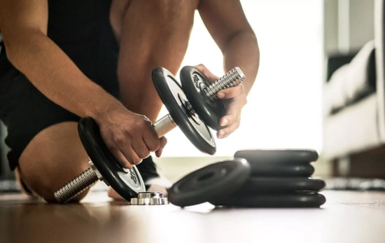 Una persona se prepara para hacer pesas en un gimnasio casero Una persona se prepara para hacer pesas en un gimnasio casero
