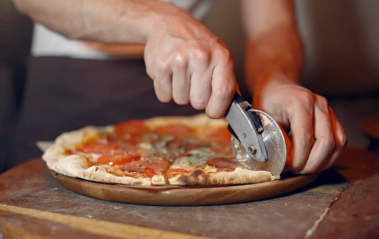 Una persona corta una pizza / FREEPIK - prostooleh Una persona corta una pizza / FREEPIK - prostooleh